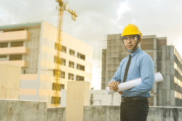 smiling young architect or engineering builder in hard hat with tablet over group of builders at...