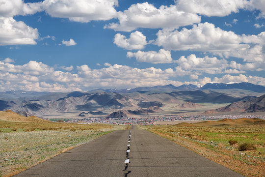 Empty Asphalt road in Mongolia  with mongolian town Bayan-Olgii (Bayan-Ulgii or Ulgii) on background