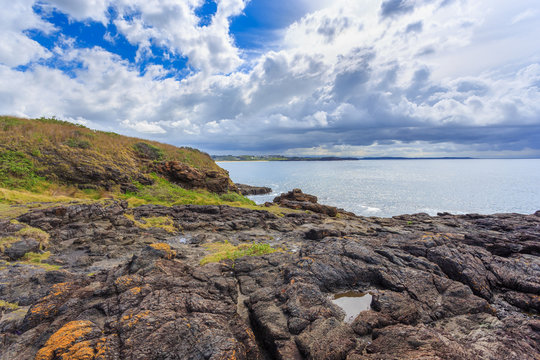 Headland and cliff face showing contact of Kiama Sandstone and Bumbo Latite with rock platform, Unusual coastal rock formations at kiama, New South Wales, Australia.