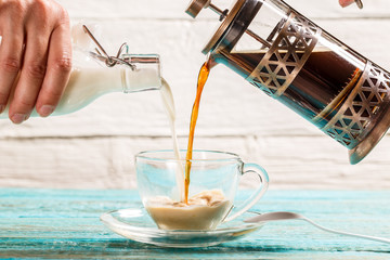 Pouring coffee and milk into a cup
