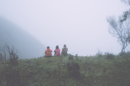 group of people siting on hill with mist