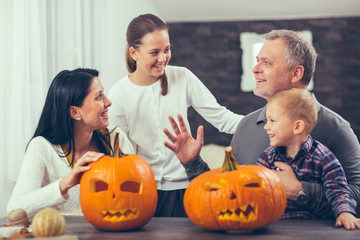 Family carving big orange pumpkin for Halloween and having fun