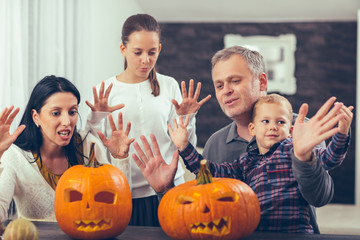 Family carving big orange pumpkin for Halloween and having fun