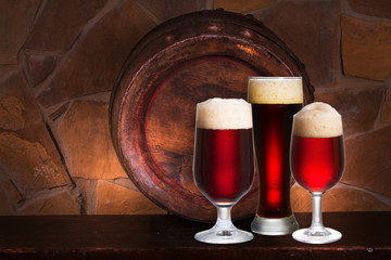 Set of various glasses of beer in cellar, pub or restaurant. Beer glasses, old beer barrel and brick wall on background. Still life with ale