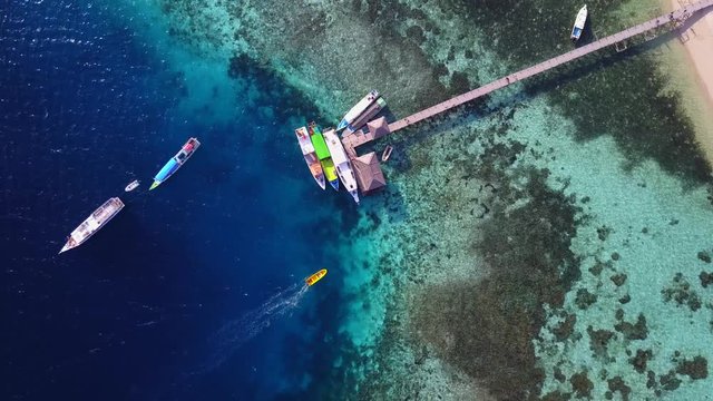 Beautiful aerial scenery footage of pier and boats on the Kanawa Island Resort with turquoise water at East Nusa Tenggara, Indonesia. Shot in 4k resolution