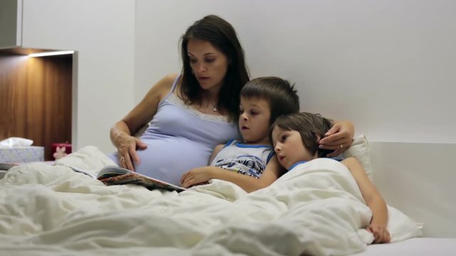 Pregnant mum, reading bedtime story for her sons