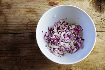 sliced red onions in a white bowl on a rustic wooden background with copy space, preparing vegetables for cooking, top view from above - Powered by Adobe