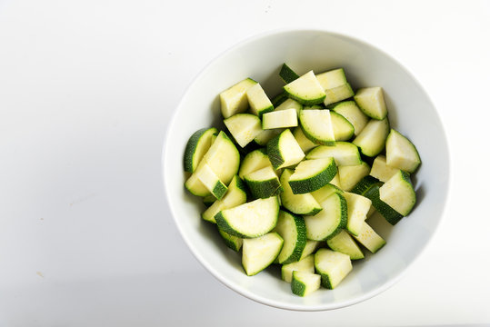 sliced zucchini, prepared vegetables in a white bowl on a light gray background, copy space, top view from above