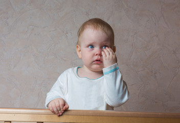 A child stands in the crib and crying