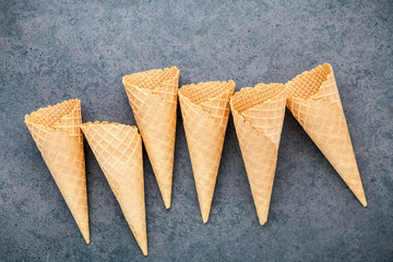 Flat lay ice cream cones collection on dark stone background . Blank crispy ice cream cone with copy space for sweets menu design.