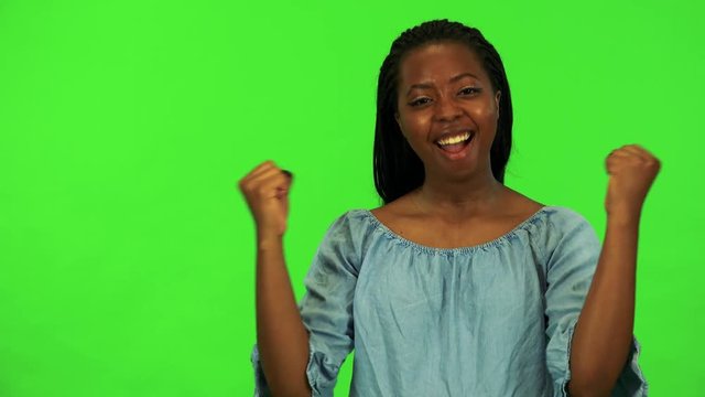 A young black woman celebrates - green screen studio
