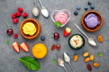 Flat lay ice cream with various fruits raspberry ,blueberry ,strawberry ,orange and cherry  setup on dark stone background . Summer and Sweet menu concept.