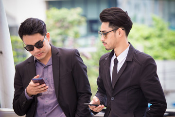 Two businessmen are discussing about work by using his smartphone to show the information and detail of project. with serious face. Businessman is checking email and news from his smart phone