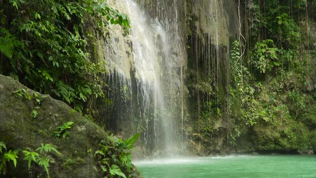 Waterfall in green forest in jungle. Beautiful waterfall in the mountains. Tropical rain forest with waterfall. Philippines, Cebu. 4K video. Travel concept.