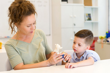 teacher woman playing with child boy with finger puppets in the classroom
