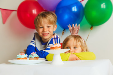 happy little girl and boy blowing candles at birthday party