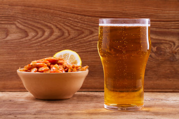 Beer and shrimps in bowl on wooden background. Glass of beer and prawns. Ale