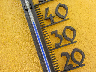 thermometer in yellow wall measuring external air temperature over forty celsius degrees