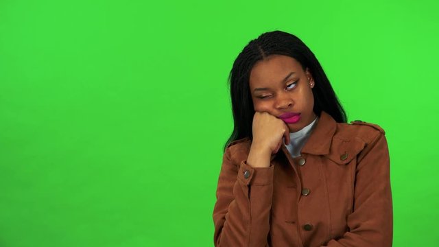 A young black woman is bored and looks around - green screen studio