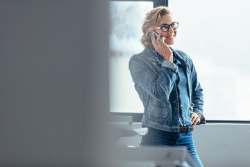 Smiling woman talking on smartphone in workplace