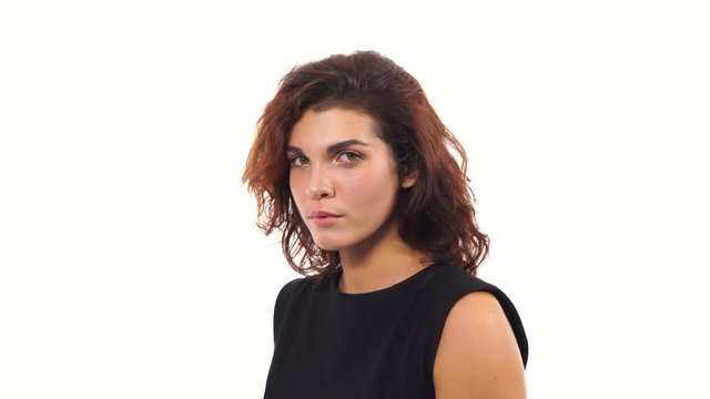 Closeup view of a depressed young woman in black dress looking at the camera isolated on white background