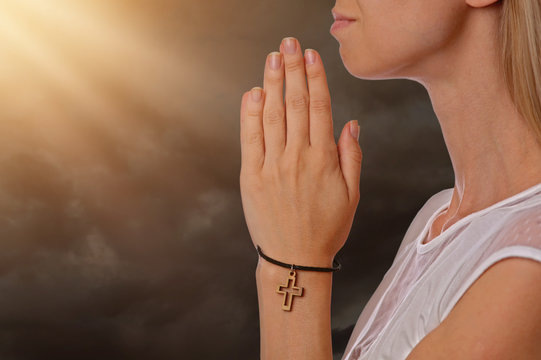 Woman praying holding christian cross on hand, faith, religion concept