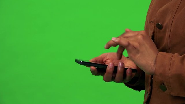 A black woman works on a smartphone - closeup - green screen studio