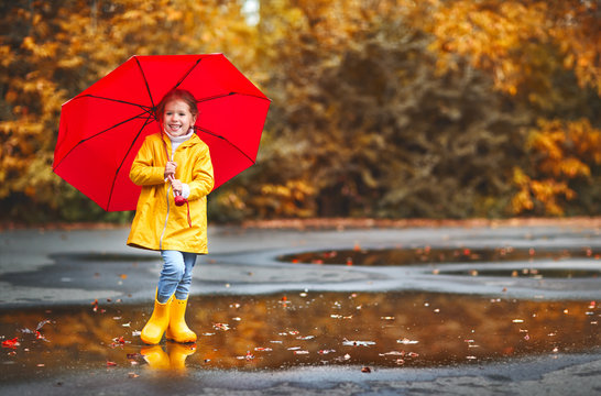 happy child girl with an umbrella and rubber boots on autumn walk.