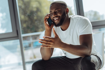 Overjoyed young afro american man talking on smartphone