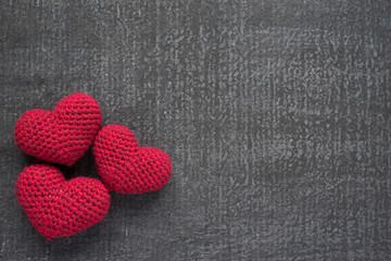 Crocheted red hearts on a grunge board