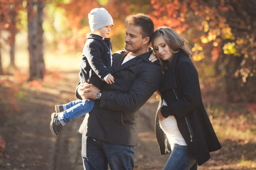 Obraz premium Young happy family have fun and walking in the autumn park. Pregnant woman with husband and little son