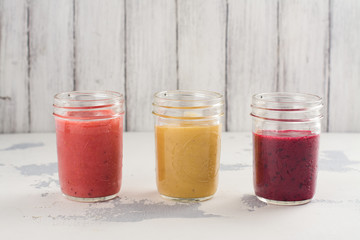 Assortment of bright fruit and berry smoothies on white table. Summer refreshing drinks. Space for text