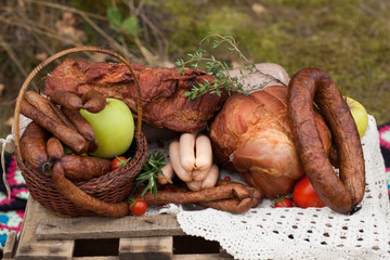 picnic - cured meat, sausages in a basket on the blanket