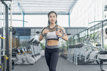 Fototapeta premium Fitness woman in training showing exercises with exercise-machine in gym