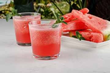 Watermelon smothie and slices with lemon on light gray background