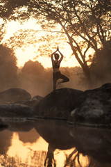 Young girl doing yoga fitness exercise outdoor in beautiful landscape. Morning sunrise.