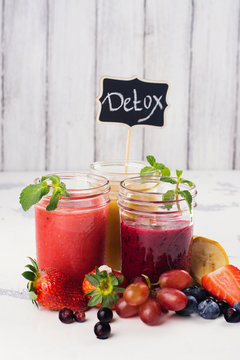 Assortment of bright fruit and berry smoothies on white table. Summer refreshing drinks. Detox or diet concept