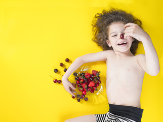 Cute boy child eating healthy organic food, fresh fruit.Yellow background with space for text or image.