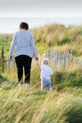 Child and grandmother walking together outside at the beach