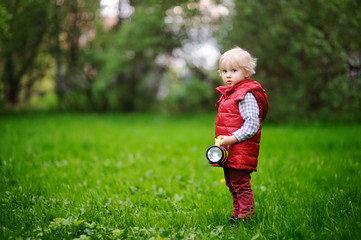 Cute toddler boy playing outdoors at cold summer or spring day