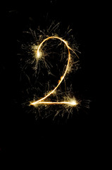 "2" number drawn with bengali sparkles isolated on black background,number from sparkler on black background