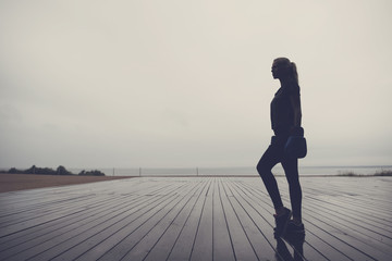 Silhouette of a young boxer woman standing on a wooden sports-ground - Powered by Adobe