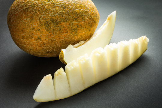 Yellow organic cantaloupe melon and slices isolated on black.