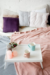 Breakfast in bed. Modern bedroom in pastel colors. Coffee and strawberries on small table decorated candles. Romantic concept and tendance between couples, close up