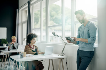 Businessman using tablet and standing near window in modern office