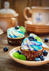 Gentle cupcake with cream and berries on adark wood background