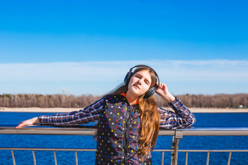Happy teenage girl listenind to music and time in the city