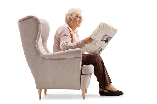 Mature woman sitting in an armchair and reading a newspaper
