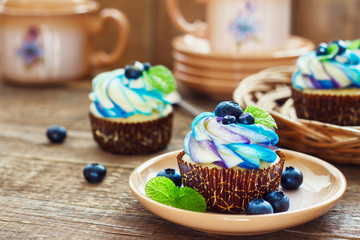 Gentle cupcake with cream and berries on adark wood background