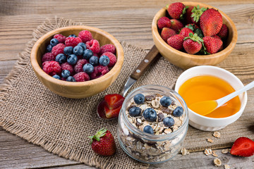 Healthy breakfast,  yogurt with flasks, honey  and berries on rustic wooden table